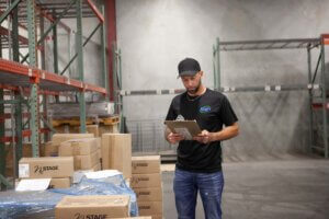 A courier reviewing a checklist on a clipboard in the Xcel Delivery warehouse