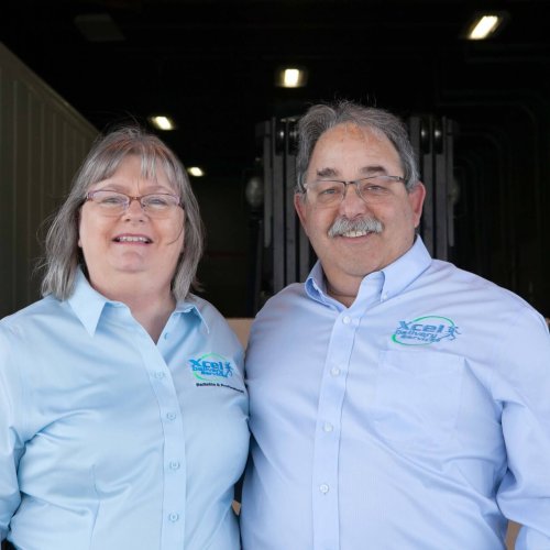 The founders of Xcel Delivery, a man and woman wearing blue button-down shirts